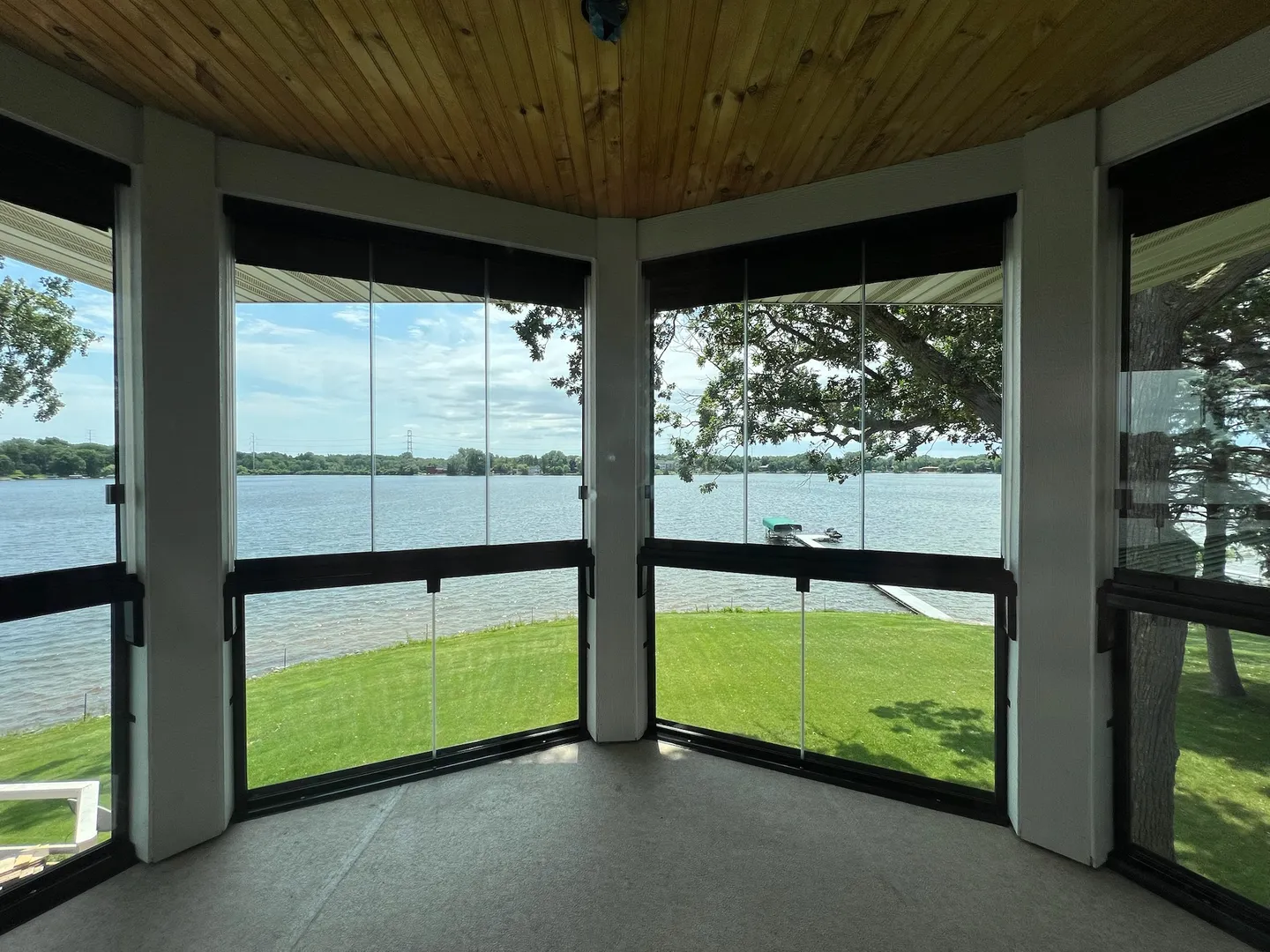 Lake porch with a fixed lower glass section and taller glass panels above, lake and dock beyond