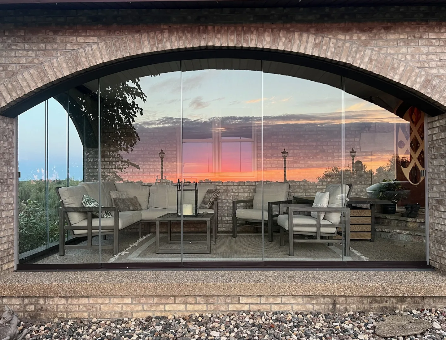 Brick arched porch opening glazed with glass, sunset over the water