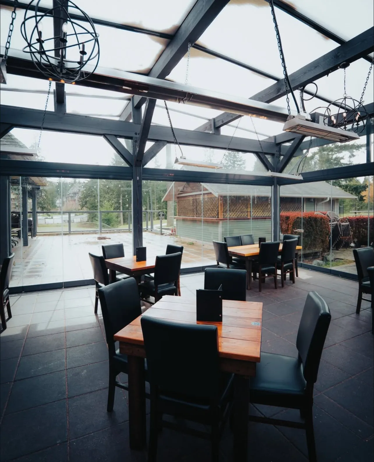 Restaurant dining tables inside a commercial glass patio enclosure