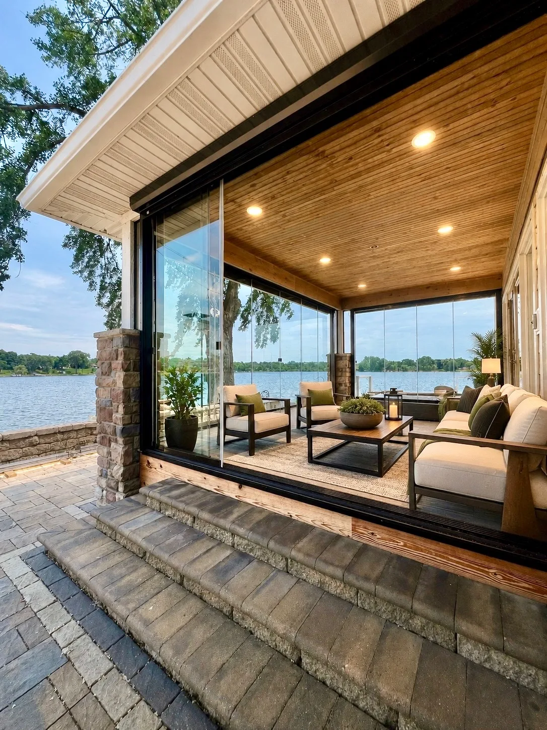 Glazed porch with a wood ceiling opening onto stone steps and the lake