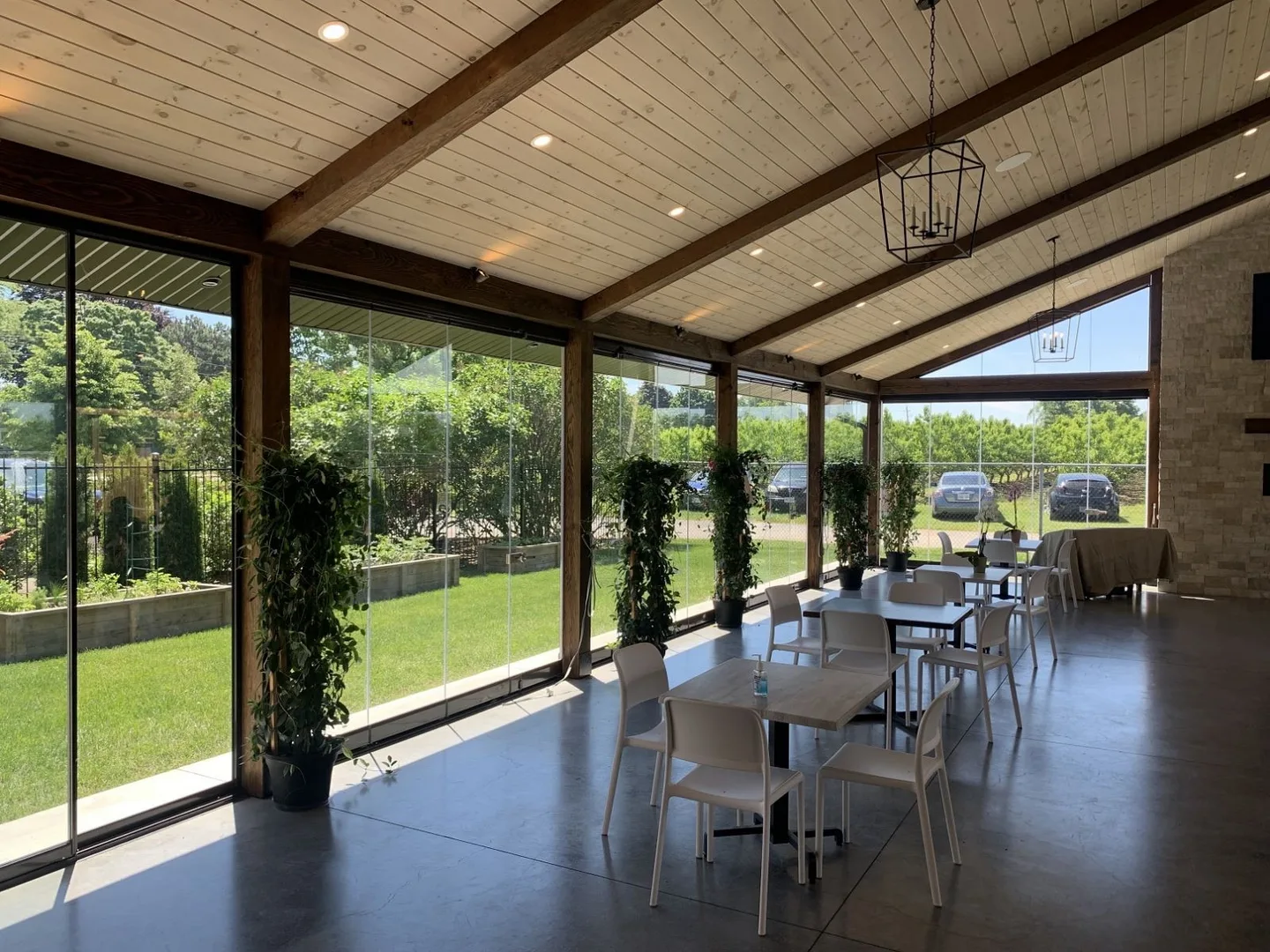 Dining tables on a glass-enclosed patio with a dark tile floor