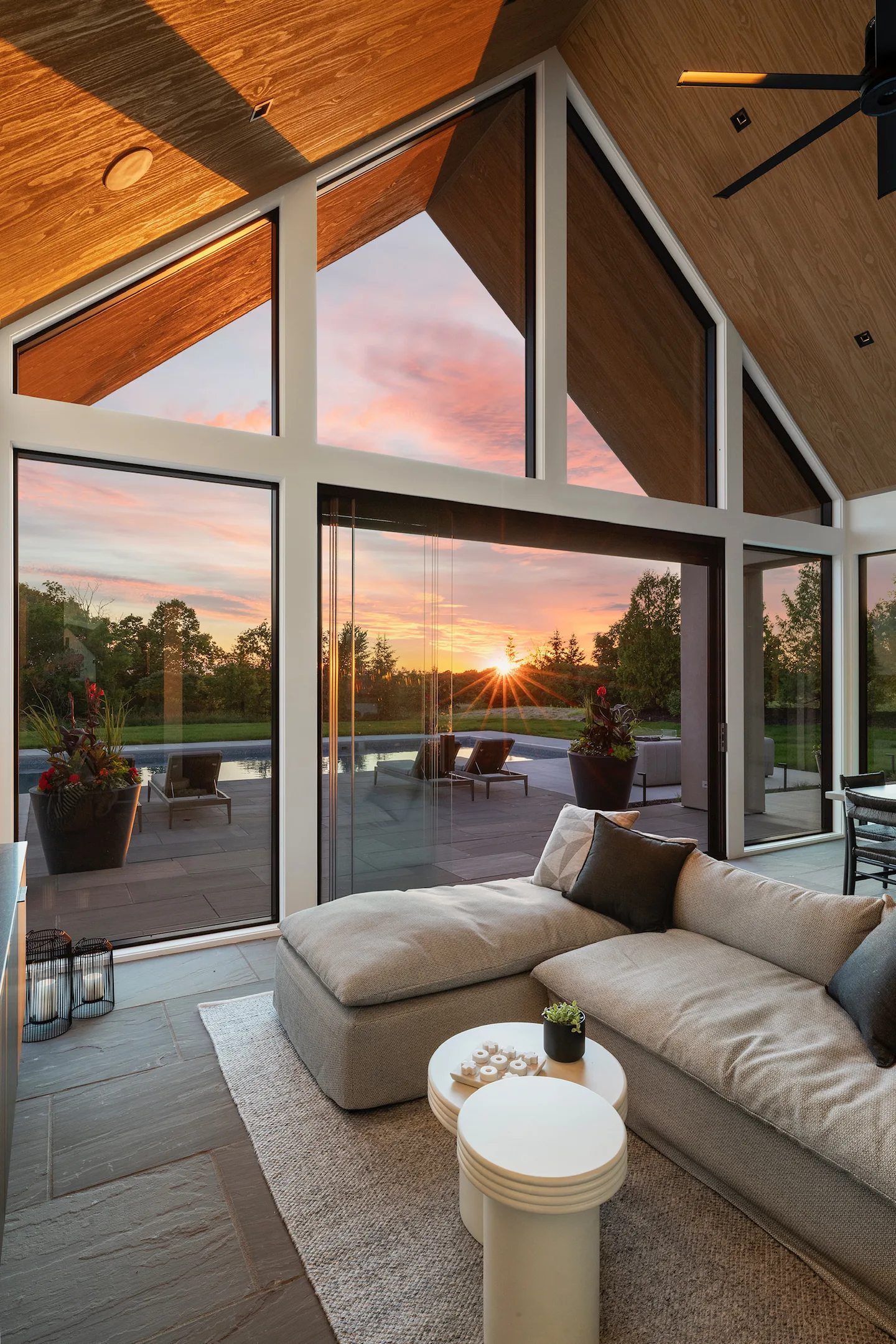 Summer sunset over the lake seen from a wood-vaulted porch behind frameless glass